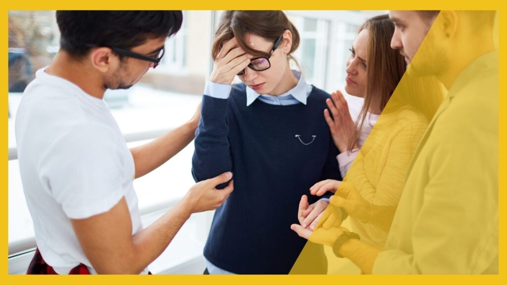 Tipps Leistungsbeurteilungen; Bild zeigt eine Gruppe von Mitarbeitern um eine Frau, die ihren Kopf hält und die getröstet wird